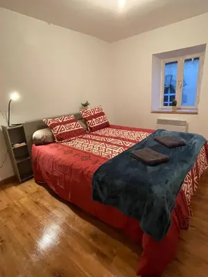 a bedroom with a bed with red sheets and a window at Appartement centre-ville in Carcassonne