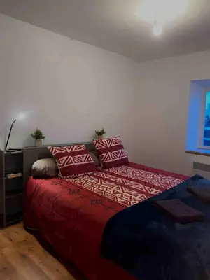 a bedroom with a bed with red sheets and pillows at Appartement centre-ville in Carcassonne