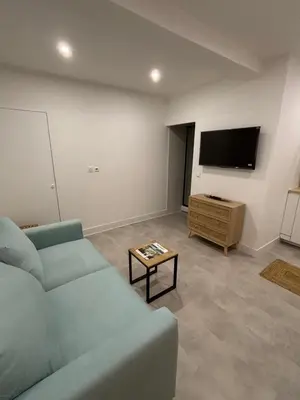 a living room with a blue couch and a flat screen tv at Studio O Fil du Vent in Gruissan