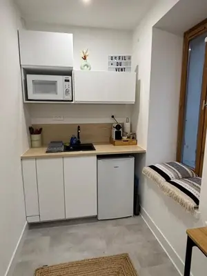 a small kitchen with white cabinets and a microwave at Studio O Fil du Vent in Gruissan
