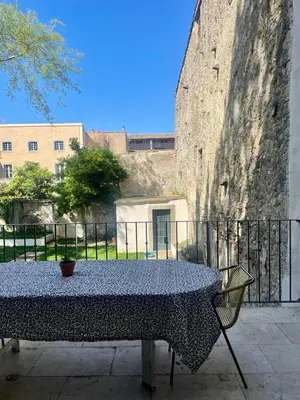 a table in front of a large stone wall at Maison Hortense Carcassonne in Carcassonne