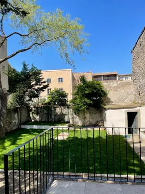 a fence in front of a building with a yard at Maison Hortense Carcassonne in Carcassonne