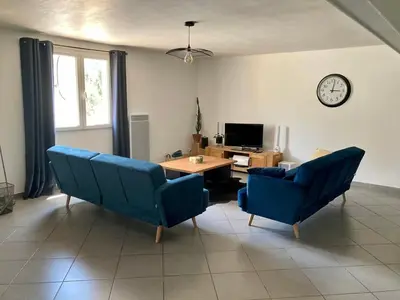 a living room with blue chairs and a table and a clock at Gite belle vue in Olargues