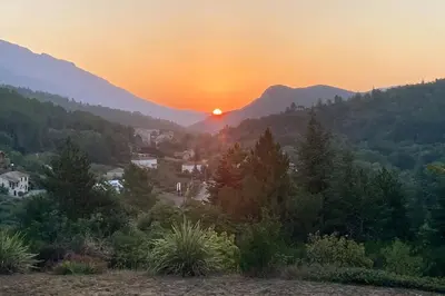 a sunset in the mountains with a town and trees at Gite belle vue in Olargues