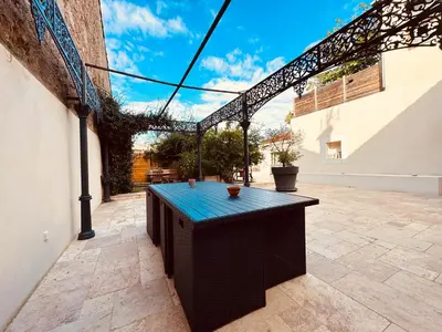 a patio with a black table in a courtyard at À 1min d'une base nautique Maison spacieuse avec piscine in Puicheric
