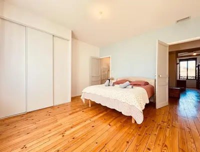 a bedroom with a bed and a wooden floor at À 1min d'une base nautique Maison spacieuse avec piscine in Puicheric
