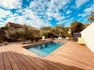 a backyard with a swimming pool and a wooden deck at À 1min d'une base nautique Maison spacieuse avec piscine in Puicheric