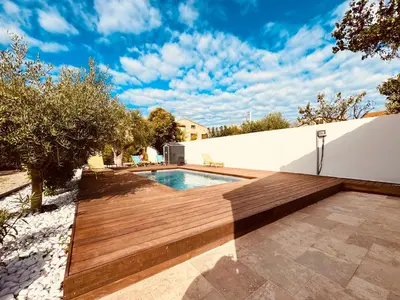 a backyard with a wooden deck and a swimming pool at À 1min d'une base nautique Maison spacieuse avec piscine in Puicheric