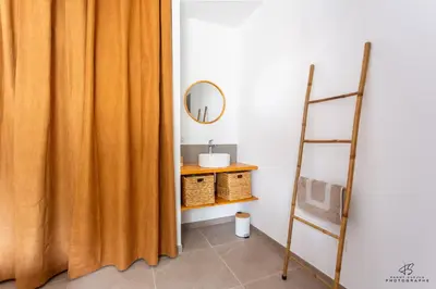 a bathroom with an orange shower curtain next to a ladder at Clos de la Pounso in Lapalme