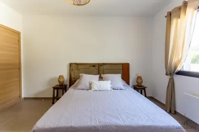 a bedroom with a white bed with two tables at Clos de la Pounso in Lapalme