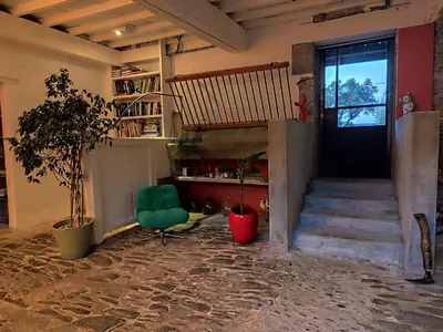 a living room with a staircase and a green chair at Les Grands Cyprès - chambres d'hôtes in Conques-sur-Orbiel