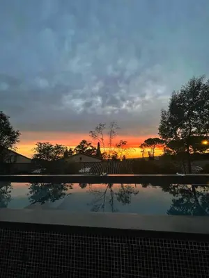 a sunset with a reflection in a swimming pool at Les Grands Cyprès - chambres d'hôtes in Conques-sur-Orbiel