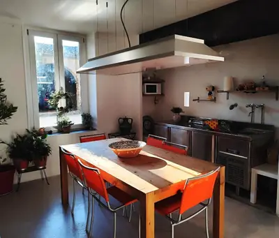 a kitchen with a wooden table and orange chairs at Les Grands Cyprès - chambres d'hôtes in Conques-sur-Orbiel