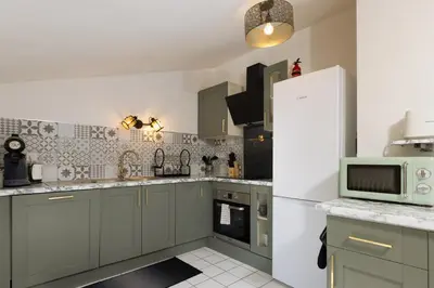 a kitchen with green cabinets and a white refrigerator at Loft Sénéchal - Rare Elegance in Carcassonne