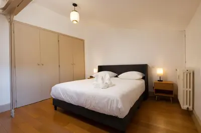 a bedroom with a large bed with white sheets and pillows at Loft Sénéchal - Rare Elegance in Carcassonne