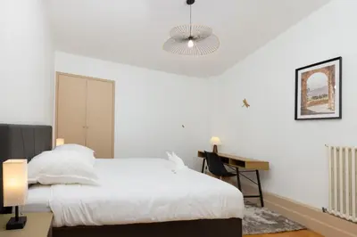 a white bedroom with a bed and a desk at Loft Sénéchal - Rare Elegance in Carcassonne