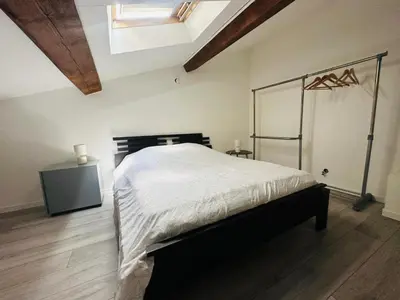 a bedroom with a bed in a room with wooden floors at Appartement T3 proche centre-ville NARBONNE in Narbonne