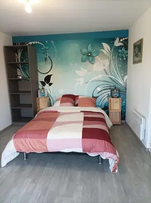 a bedroom with a large bed with a floral wall at Chez Sabine la Campagne HAUT in Narbonne