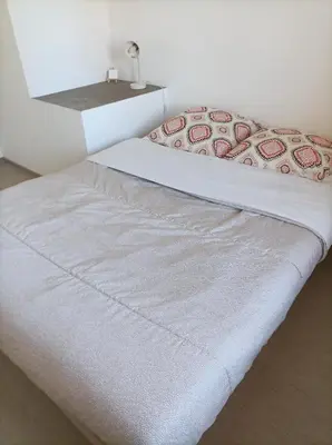 a white bed in a room with a white wall at Chez Sabine la Campagne HAUT in Narbonne