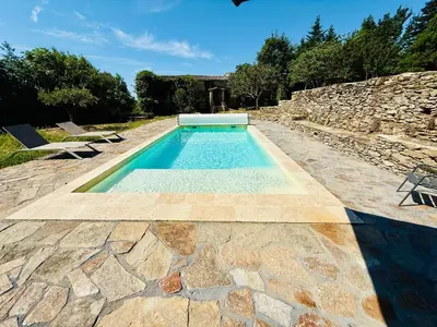 a swimming pool in a yard with a stone wall at Domaine Riplou - Maison de Campagne avec piscine in Verdun-en-Lauragais