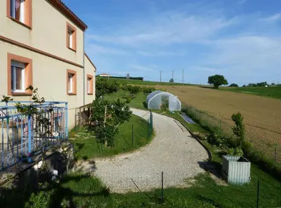 a house with a garden next to a field at Gites des Camparros in Nailloux