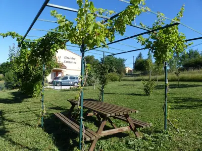 a wooden picnic table in a field with trees at Gites des Camparros in Nailloux
