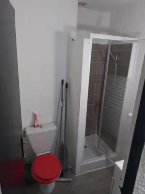 a bathroom with a shower and a toilet with a red seat at Mas Dels Caminhs in Villepinte