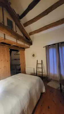 a bedroom with a white bed and a window at La Maison du chataignier in Cassagnolles