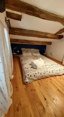 a small bed in a room with wooden floors at La Maison du chataignier in Cassagnolles