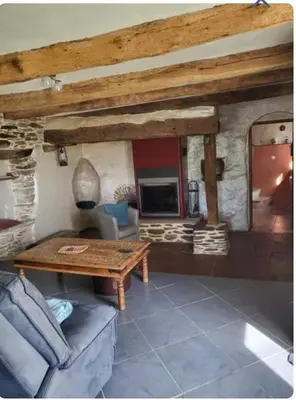a living room with a table and a stone fireplace at La Maison du chataignier in Cassagnolles