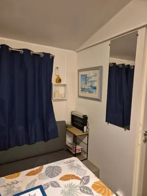 a bedroom with a bed and a blue curtain at Mobil-home Climatisé 6 personnes à Port La Nouvelle in Port-la-Nouvelle