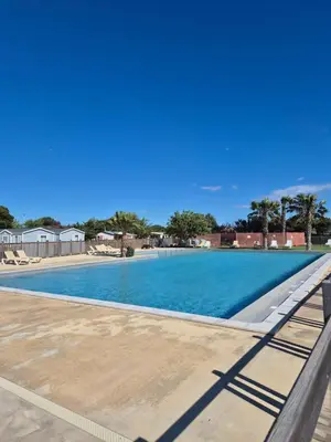 a swimming pool with blue water and palm trees at Mobil-home Climatisé 6 personnes à Port La Nouvelle in Port-la-Nouvelle