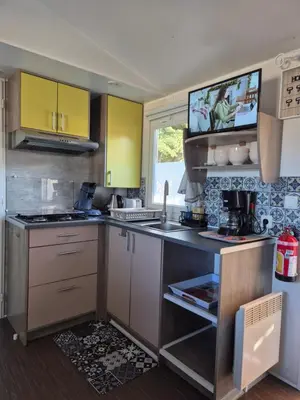 a kitchen with yellow cabinets and a counter top at Mobil-home Climatisé 6 personnes à Port La Nouvelle in Port-la-Nouvelle