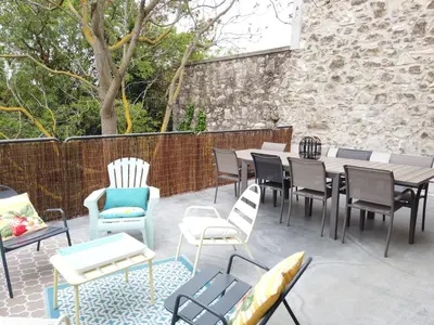 a patio with tables and chairs and a brick wall at La Galinette Family Loft in Sigean