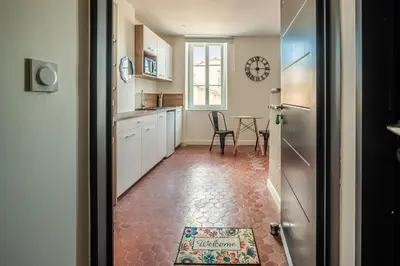 a kitchen with a table and a clock on the wall at Studio Blue Délice in Narbonne
