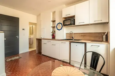 a kitchen with white cabinets and a glass table at Studio Blue Délice in Narbonne