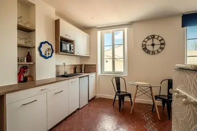 a kitchen with white cabinets and a clock on the wall at Studio Blue Délice in Narbonne