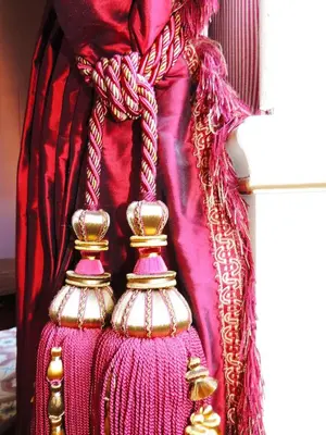 a red curtain with gold jewelry on it at Chateau de Paraza in Paraza