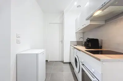 a white kitchen with a stove and a washer at T2 apartment in the heart of Cuxac-d'Aude in Cuxac-dʼAude