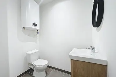a white bathroom with a toilet and a sink at T2 apartment in the heart of Cuxac-d'Aude in Cuxac-dʼAude