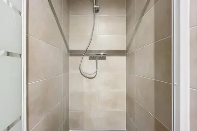 a shower with a hose in a bathroom at T2 apartment in the heart of Cuxac-d'Aude in Cuxac-dʼAude