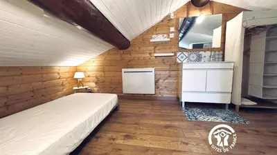 a bedroom with a bed in a room with wooden walls at Le moulin de cameliere in Caudebronde