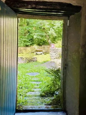 an open door to a yard with a garden outside at Le moulin de cameliere in Caudebronde