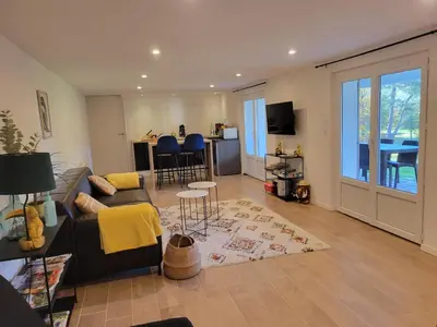 a living room with a couch and a table and a kitchen at Appartement au cœur du golf in Pont-de-Larn