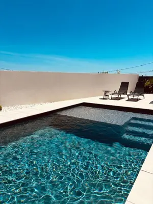 a swimming pool with two chairs and a table at Villa moderne privée avec piscine, vue montagne 3 chambres in Pennautier