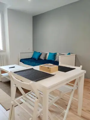 a white table and chairs in a room with a couch at Le Secret du Clocher in Pamiers