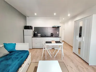 a bedroom with a bed and a table and a kitchen at Le Secret du Clocher in Pamiers