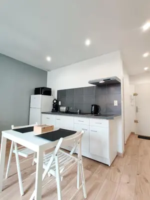 a white kitchen with a white table and chairs at Le Secret du Clocher in Pamiers