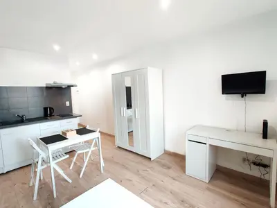 a white kitchen with a desk and a table with chairs at Le Secret du Clocher in Pamiers