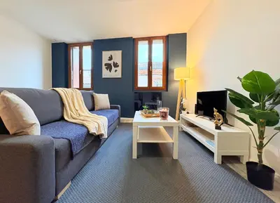 a living room with a blue couch and a tv at Le Faubourg in Pamiers